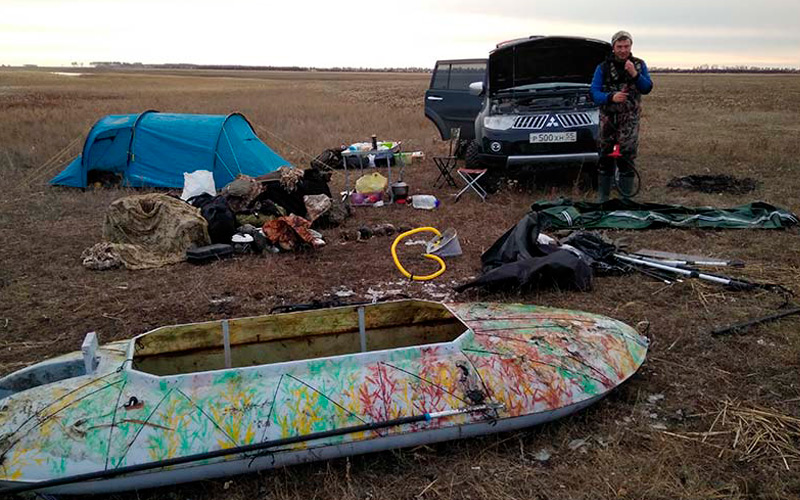 лодка, палатка и машина охотника на поле